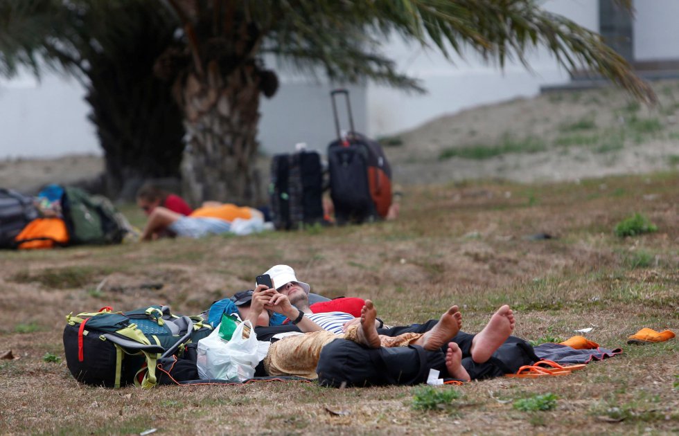 Turistas extranjeros duermen sobre el cesped mientras esperan su vuelo en el aeropuerto Internacional Praya en Lombok (Indonesia) hoy, 6 de agosto de 2018, tras el terremoto de magnitud 6,9 que sacudió la noche del domingo. 