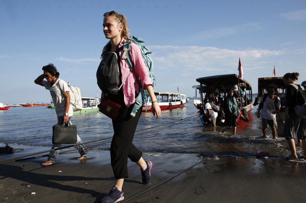 Turistas extranjeros cargan sus pertenencias mientras desembarcan de un bote, el 7 de agosto de 2018.