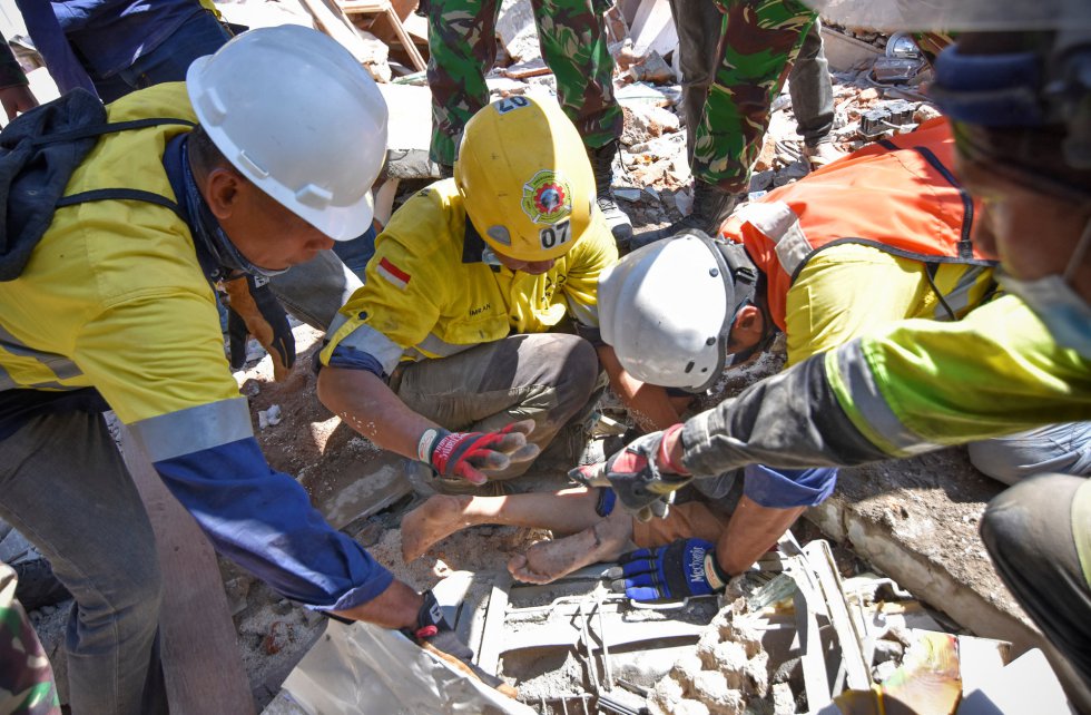 Trabajadores rescatan con vida a una mujer atrapada entre los escombros, el 7 de agosto de 2018 en Tanjung. 