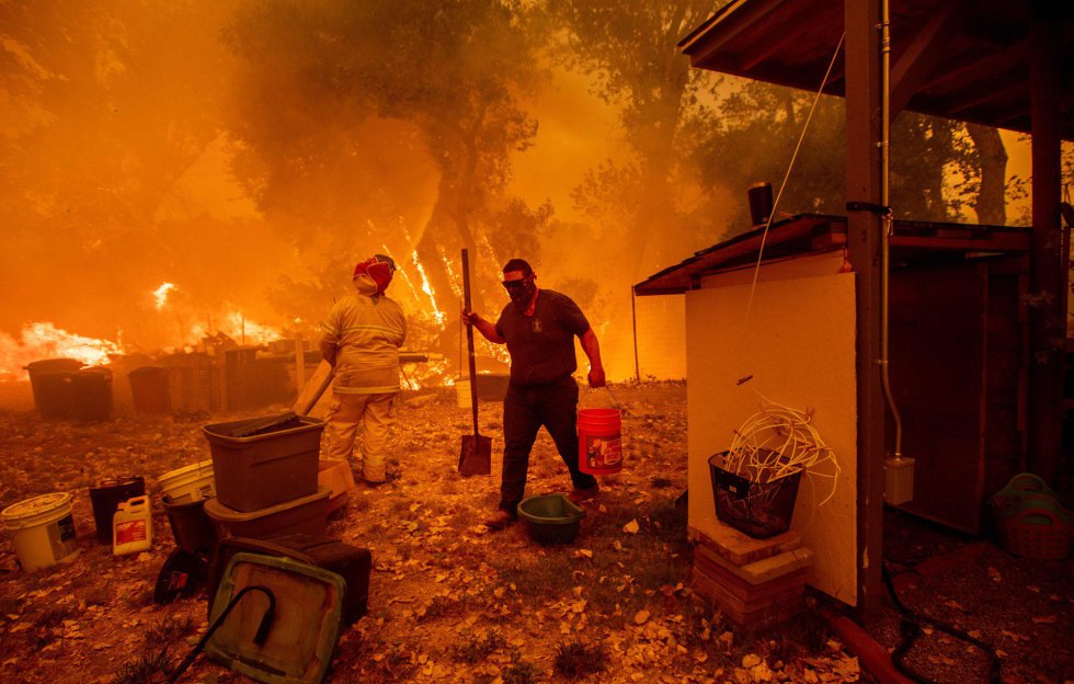 Un residente transporta un cubo de agua mientras lucha para salvar su casa del incendio de Ranch Long New Valley Rd, cerca de Clearlake Oaks, California, el 4 de agosto de 2018.