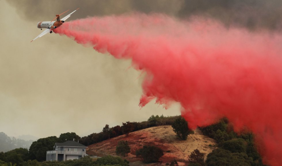 Un avión cae retardante sobre una propiedad amenazada por un incendio forestal, en Lakeport, California, el 30 de julio de 2018.