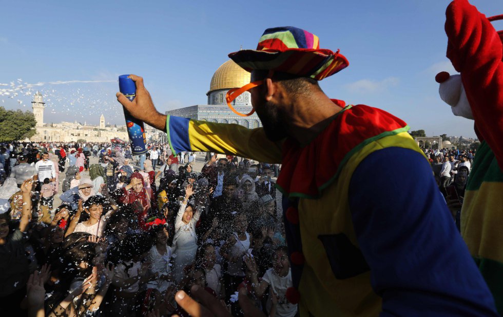 Un payaso dispara espuma a los visitantes para celebrar la llegada del Eid al-Adha, en la ciudad vieja de Jerusalén, el 21 de agosto de 2018.rn