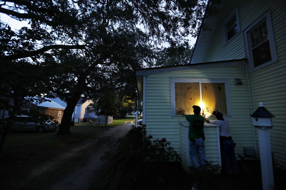 Russell Meadows, izquierda, ayuda al vecino Rob Muller a asegurar su casa antes del huracán Florence en Morehead City, Carolina del Norte.