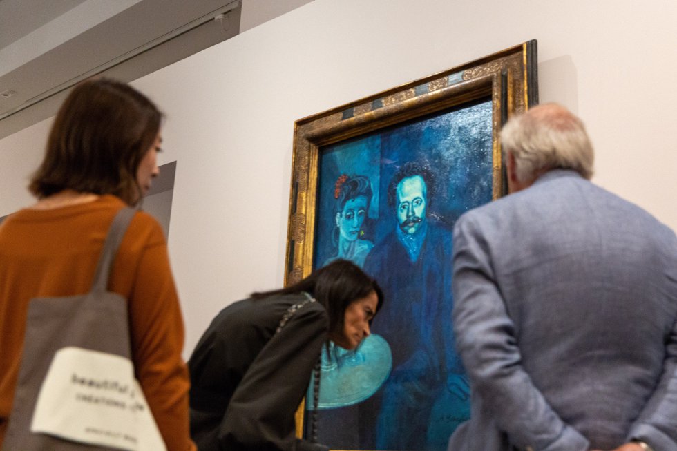 Vários visitantes observam uma das pinturas de Picasso.