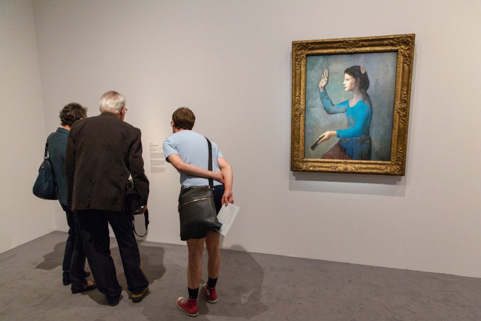 Três pessoas leem a informação sobre uma das obras na exposição do Museu de Orsay.