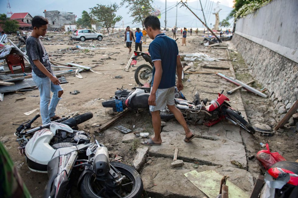 Varios vecinos de Palu observa unas motocicletas daÃ±as por el tsunami y el terremoto, el 29 de septiembre.