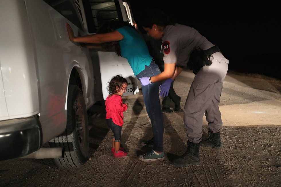 Una niña hondureña de dos años llora mientras su madre es cacheada por un policía de la patrulla fronteriza en McAllen (Texas), el 12 de junio de 2019. Los solicitantes de asilo habían cruzado el río Bravo desde México y fueron detenidos por agentes de la Patrulla Fronteriza de los Estados Unidos antes de ser enviados a un centro de procesamiento para una posible separación, en aplicación de la política de tolerancia cero de la administración Trump hacia los inmigrantes indocumentados. 