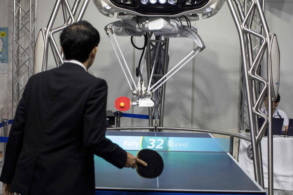 Un robot jugador de ping-pong, desarrollado por Omron, interactúa con un asistente del World Robot Summit en Tokio (Japón).