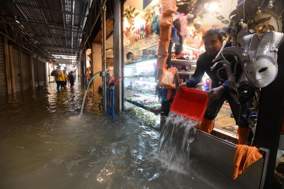 Un vendedor achica agua de su tienda en Venecia (Italia), el 29 de octubre de 2018. Seis regiones italianas están en alerta roja por el fuerte temporal y las intensas lluvias que están azotando el país en las últimas horas.