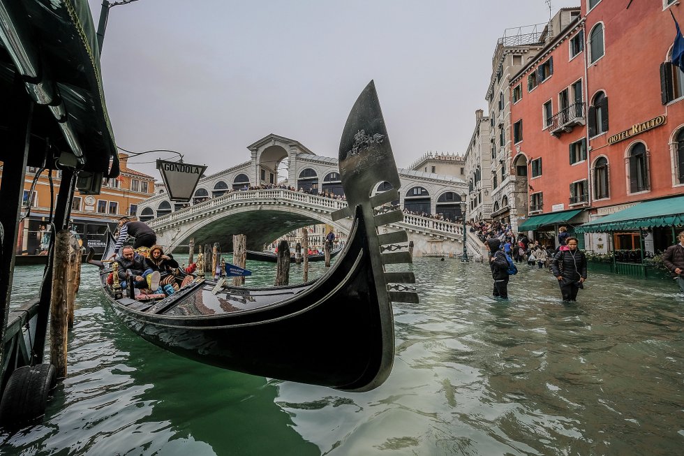 Un grupo de turistas se sube a una góndola a pesar del aviso de subida del agua en Venecia.