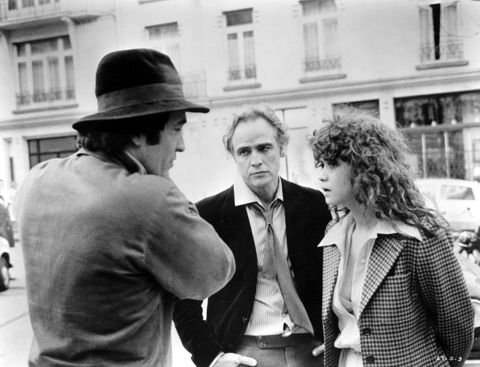 Bertolucci conversa con Marlon Brando y Maria Schneider durante el rodaje de la pelÃ­cula 'El Ãºltimo tango en ParÃ­s', en 1972. Esta pelÃ­cula causÃ³ un gran impacto en la sociedad de los 70, por el fuerte erotismo que caracterizaba el filme con numerosos planos de desnudos frontales de la mujer y, una escena particular que pasarÃ­a a la historia del cine, en la que el personaje masculino viola analmente a la mujer. La pelÃ­cula fue censurada en EspaÃ±a durante el rÃ©gimen franquista y no se estrenÃ³ hasta diciembre de 1977.