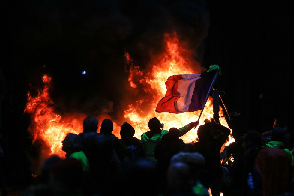 Una bandera nacional francesa junto a una hoguera durante la protesta de los 'chalecos amarillos', movimiento que nació para reclamar la bajada del precio del carburante.