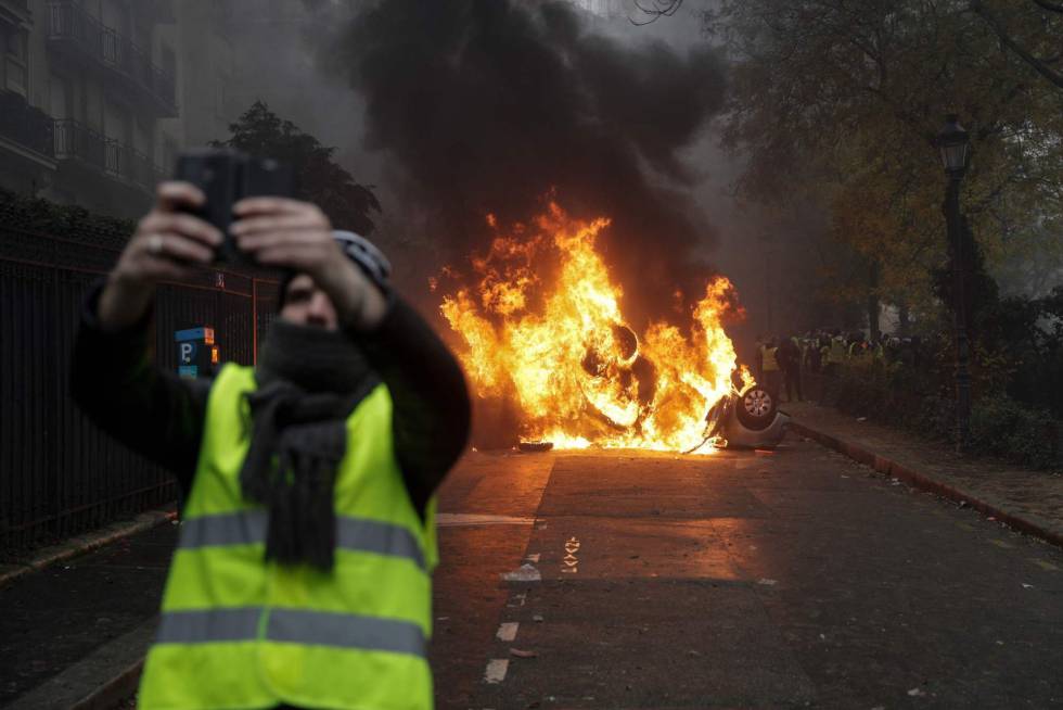 Un manifestante se hace un 'selfie' junto a un vehículo en llamas en París (Francia).