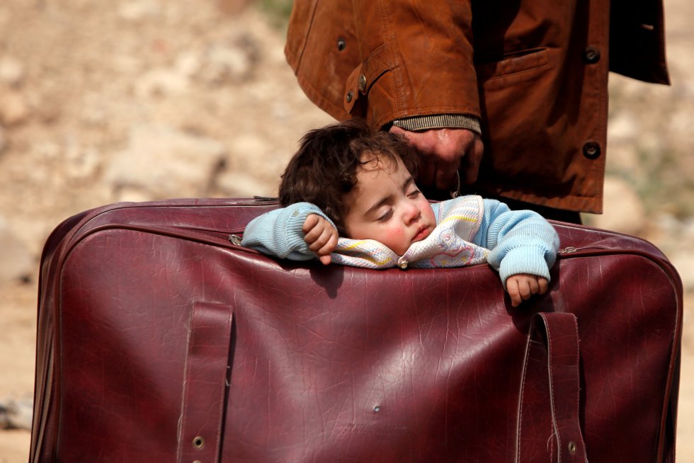 Um menino dorme enquanto é levado numa mala no povoado de Beit Sawa (Síria), em 15 de março de 2018. Os 400.000 moradores do leste da região de Guta vivem sob o cerco do Governo desde 2013, sobrevivendo a uma grave escassez de alimentos e medicamentos. Depois do início do ataque aéreo e terrestre das forças do regime, em fevereiro, 1.180 civis morreram, 250 deles em apenas 48 horas de bombardeios do regime sírio.