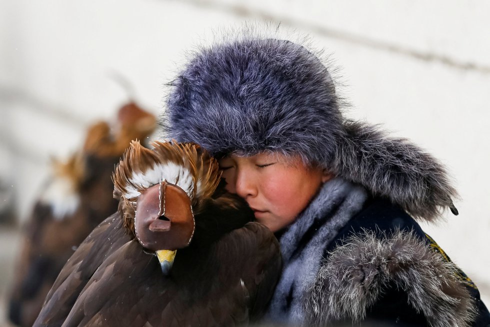 Um jovem caçador descansa junto a sua águia dourada durante um concurso de caçadores no hipódromo de Almaty (Cazaquistão), em 9 de fevereiro de 2018.