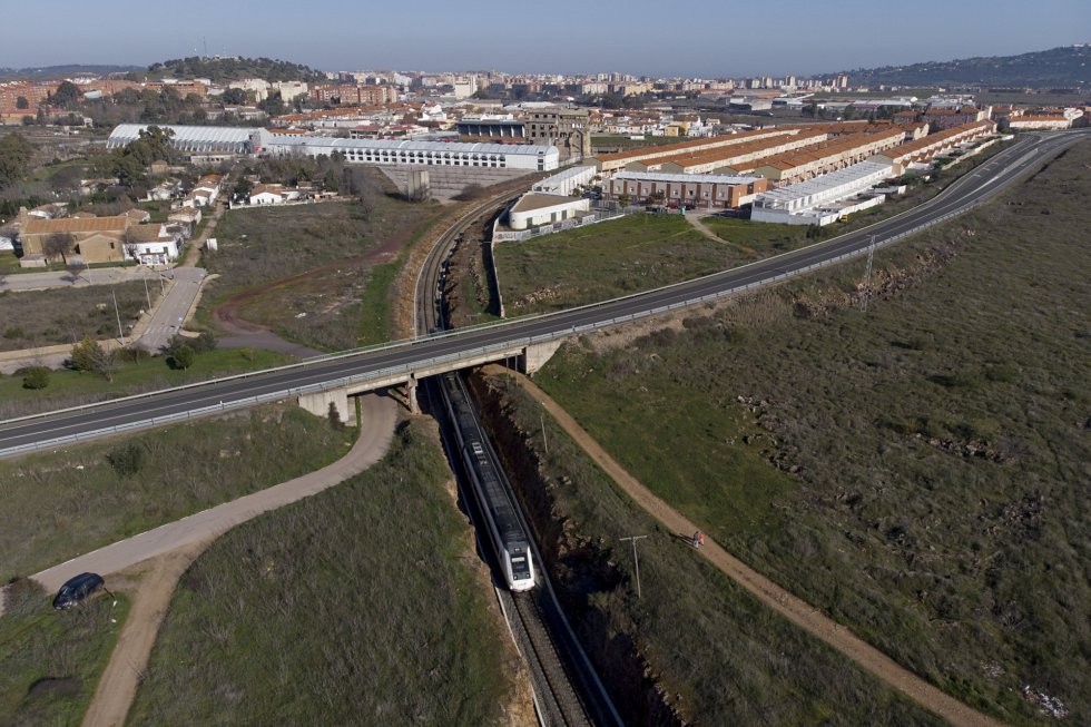 El proyecto de la alta velocidad extremeña se divide en tres tramos: Madrid-Oropesa, Oropesa-Plasencia y Plasencia-Badajoz. Se presupuestó en 3.350 millones. Zapatero dijo que estaría listo en 2010. Rajoy, que en 2015. La realidad es que el primer recorrido se encuentra en estudio; del segundo solo se ha ejecutado un 18%: 154 millones de los 823 presupuestados. Y del tercero, el más avanzado, el 75,6%; 1.065,6 de los 1.407 estimados. En la imagen, un tren circula por la vía ferroviaria que une Cáceres (al fondo) y Badajoz, bajo la carretera nacional EX-100.