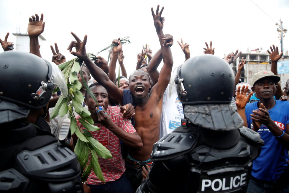 Un grupo de personas celebra los resultados frente a la policÃ­a, en Kinshasa. 