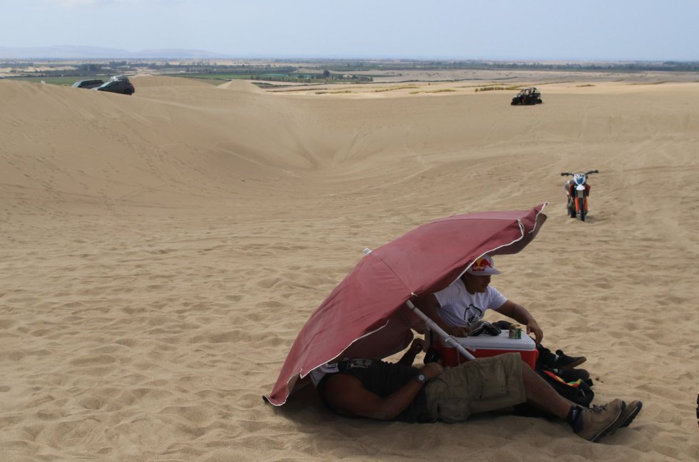 Dos hombres se protegen del sol durante la primera etapa en motos del Dakar 2019 hoy, entre las ciudades de Lima y Pisco (Perú), el 7 de enero de 2019.