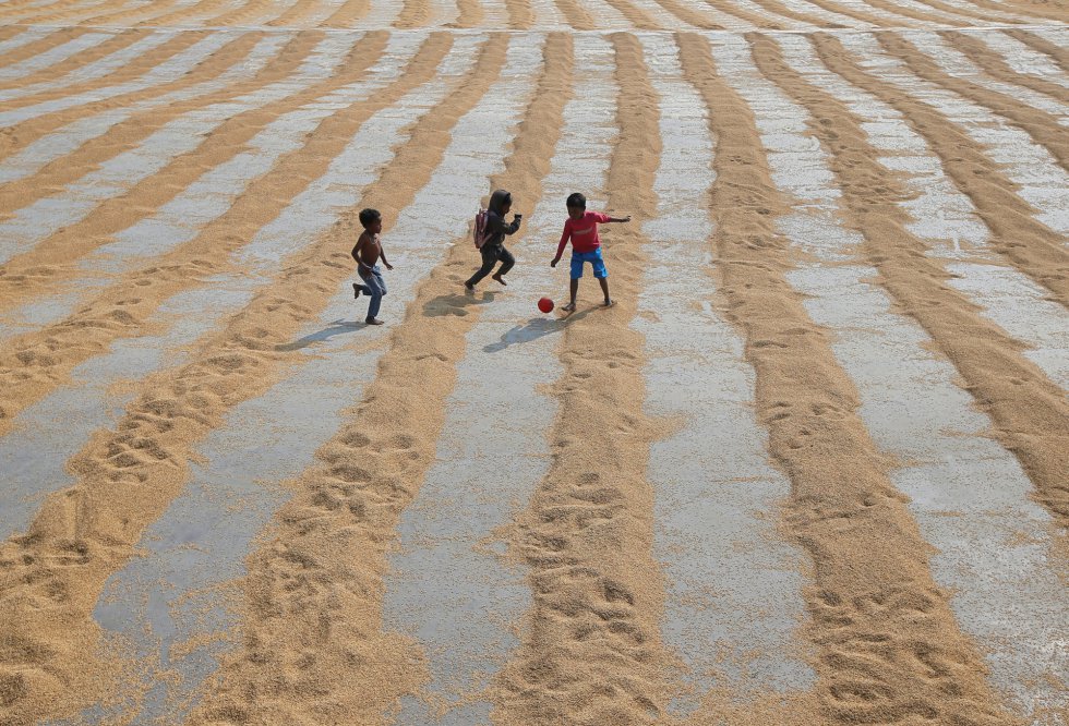 Los niños juegan con una pelota en un molino de arroz a las afueras de Calcuta (India), el 31 de enero de 2019.