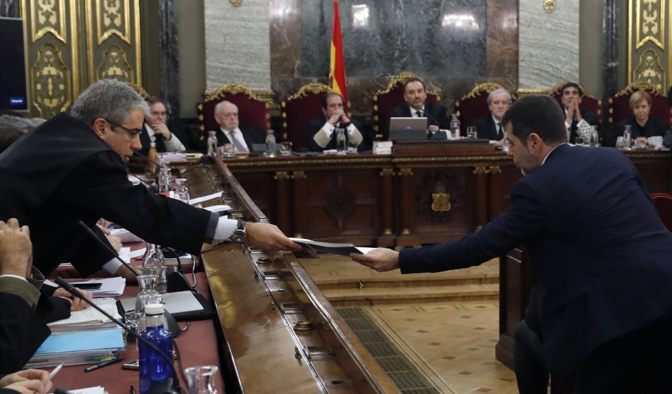 El coordinador de la defensa de los 'exconsellers' del PDeCAT y 'exconseller' de Presidencia Francesc Homs (izda) entrega un documento al expresidente de la ANC y diputado de Junts per Catalunya Jordi Sànchez, al inicio del juicio del 'procés'.