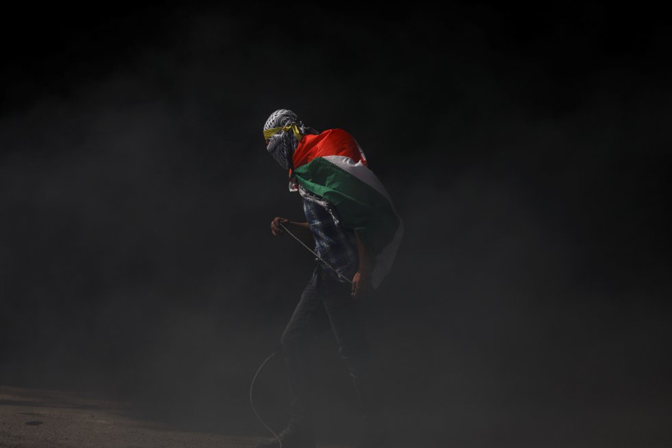 Un manifestante porta una bandera de Palestina sobre sus hombros, durante un enfrentamiento con las tropas israelíes cerca del asentamiento Bet El (Cisjordania), el 27 de marzo de 2019. Desde diciembre de 2018, la tensión se disparó en la zona tras la muerte a tiros de dos soldados y un bebé israelí. Ya para inicios de 2019, Palestina abría con un saldo de un muerto y 10 heridos por fuego israelí en una aldea palestina, al norte de Ramala.