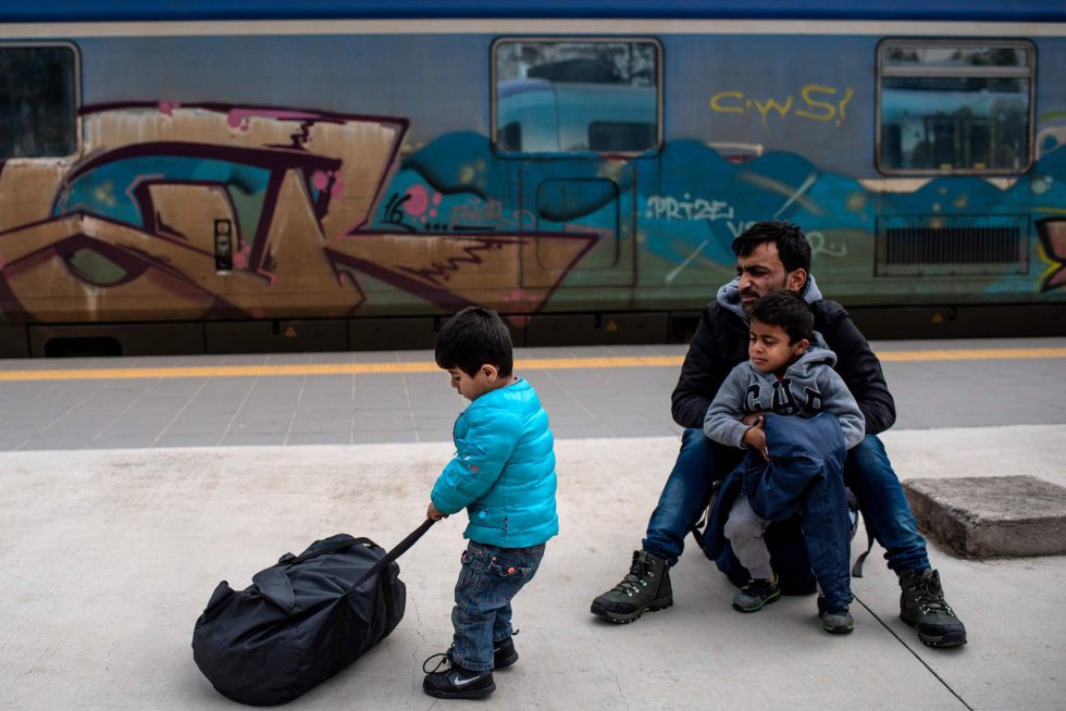 Un padre con sus dos hijos esperan en la estación de Larissis para poder partir hacia Macedonia del Norte.