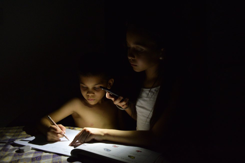 Dos niños estudian con la luz de un móvil en Maracaibo (Venezuela), el 21 de abril de 2019.