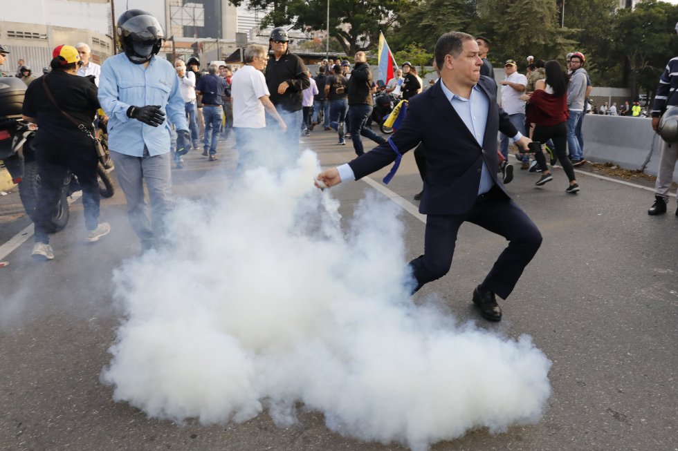 Luis Florido, diputado por Voluntad Popular, retira un bote de gas lacrimÃ³geno lanzado desde el interior de la base militar de La Carlota, este martes en Caracas.