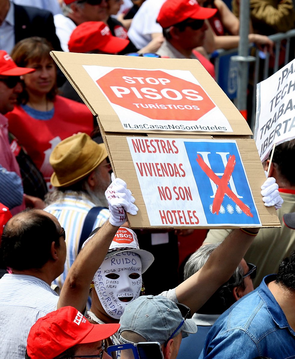 Un hombre sostiene un cartel bajo el lema "Stop pisos turÃ­sticos" durante la manifestaciÃ³n del Primero de Mayo, en Madrid.