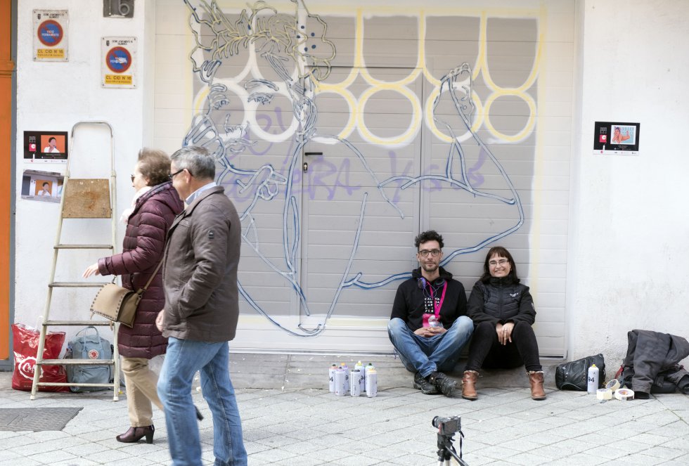 La maestra Nines Moro (sentada) realizó una encuesta con sus amigos para elegir la obra que decorarÃa su garaje en la calle del Cid. Primavera 2019', del artista palentino Daniel Revuelta, alias Fumantwo, ganó. La asociación ZOES, que cuenta con una decena de colaboradores que trabajan de manera permanente en ella, muestra varios bocetos a los vecinos para que elijan la obra que quieren que decore su cochera. Revuelta, que ha trabajado como ilustrador en el Festival Internacional de Cortometrajes de Aguilar de Campoo, su ciudad natal, se enteró del concurso del Barrio del Oeste por un familiar que vive en Salamanca.