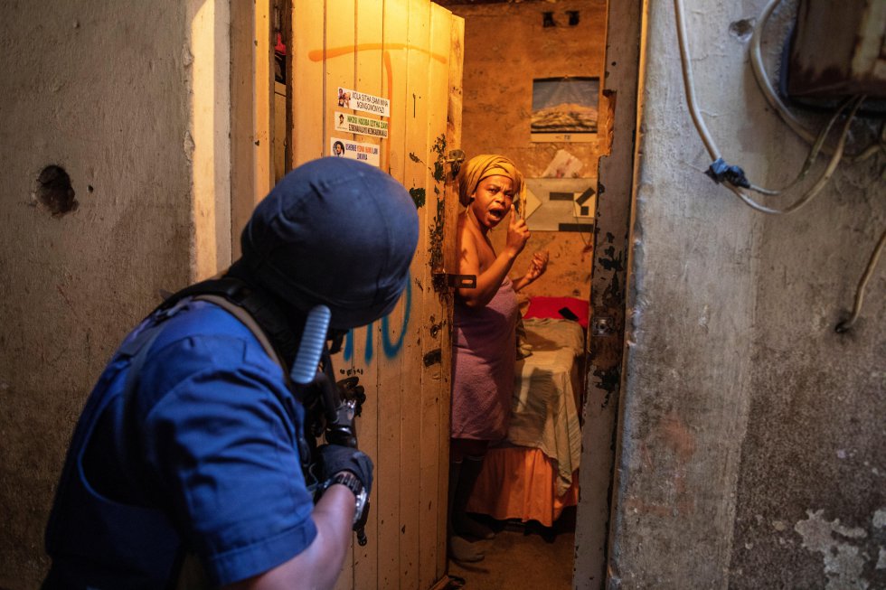 Una mujer reacciona después de que un policía irrumpiera en su habitación durante una redada policial en un edificio de viviendas secuestrado por las mafias inmobiliarias, el 12 de junio de 2019, en el centro de Johannesburgo, Sudáfrica. Aproximadamente 400 edificios de la ciudad permanecen tomados por las mafias, que luego alquilan las viviendas a inmigrantes. Las torres suelen ser tomadas a la fuerza durante la noche por parte de grupos organizados y suelen tener el mismo desenlace: la pérdida del control de su propiedad por parte del dueño y la creación de focos de delincuencia e insalubridad que van extendiéndose hasta afectar a barrios enteros.