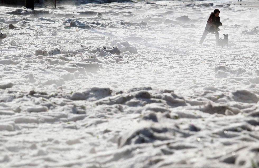 Una mujer y su perro caminan por una calle cubierta de hielo en Guadalajara (México).