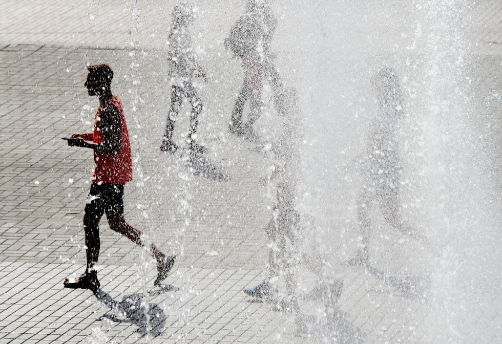 Un grupo de personas camina a través de las fuentes para refrescarse durante la ola de calor en el centro de la capital ucraniana de Kiev.