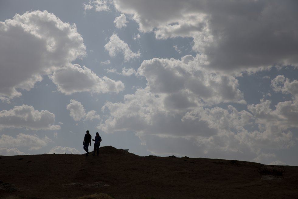 Dois arqueólogos cruzam o montículo de terra que cobre a muralha que rodeava a parte sul do povoado íbero.