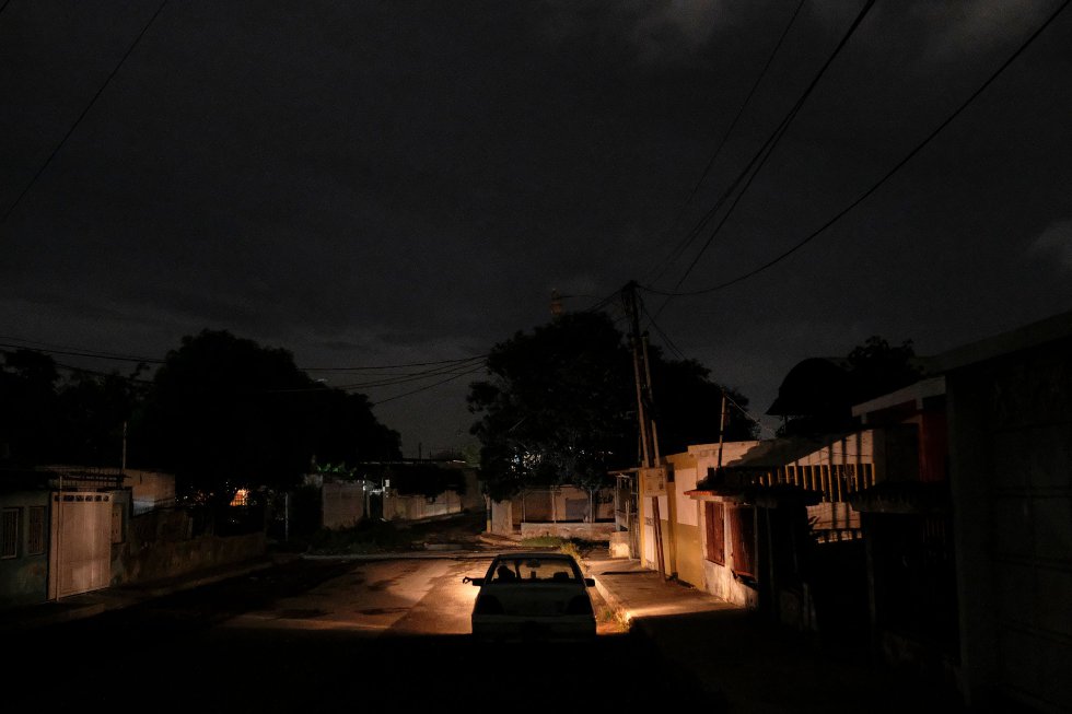 Un coche recorre una calle a oscuras por un apagón de luz en Maracaibo (Venezuela). 693 kilómetros separan lo que parecen ser dos países distintos dentro del propio territorio nacional. "Caracas es el lugar donde hay agua y luz", explica Luis Vicente León, de la firma Datanálisis.
