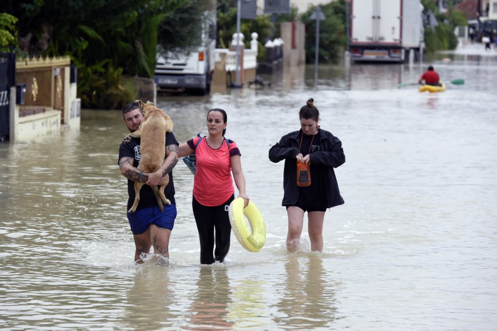 Varios vecinos caminan por una calle inundada de El Raal (Murcia), este sÃ¡bado, tras las fuertes lluvias.