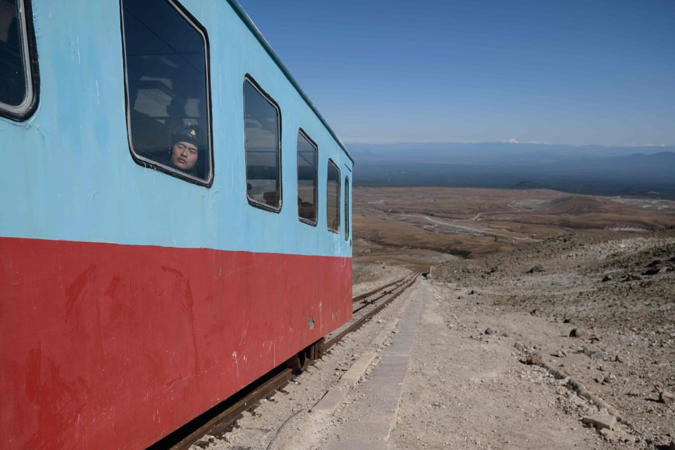 Um homem olha pela janela do funicular, onde os visitantes viajam para o topo do Monte Baekdu. O Monte Baekdu está na fronteira entre a Coreia do Norte e a República Popular da China.