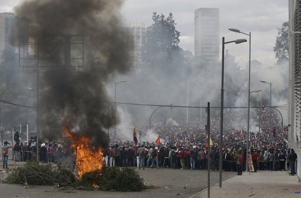 Manifestantes antigubernamentales se reúnen detrás de una barricada en llamas durante una protesta contra el presidente Lenin Moreno y sus políticas económicas.
