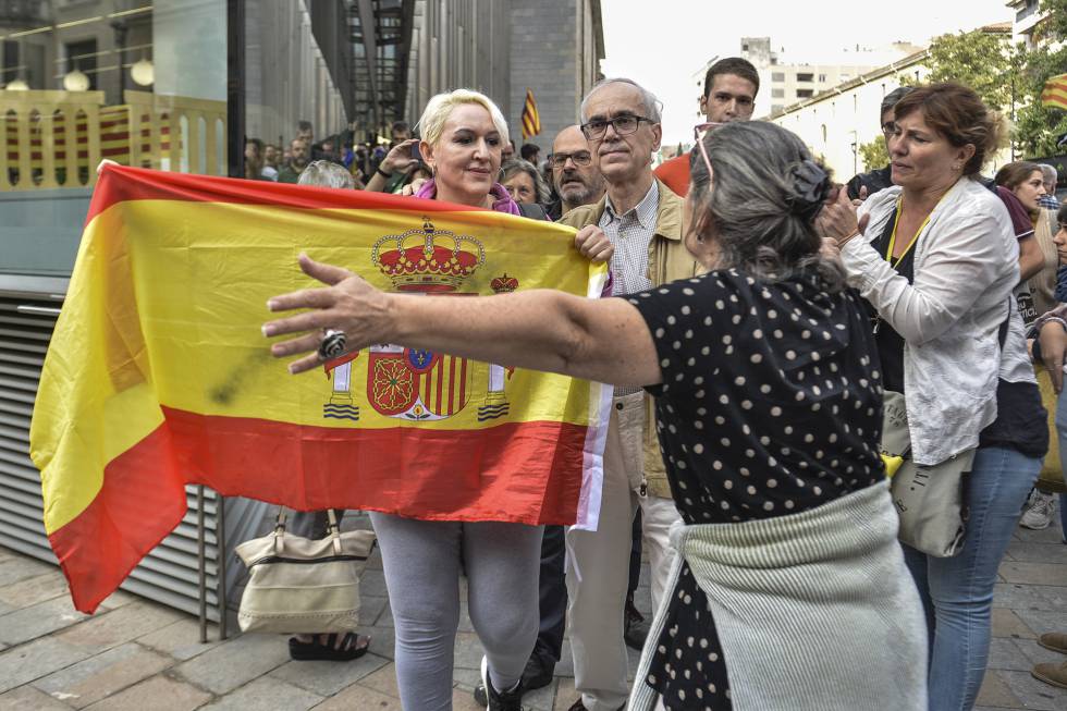 Una mujer sujeta una bandera de España mientras es increpada por un grupo de independentistas en Girona, este lunes.