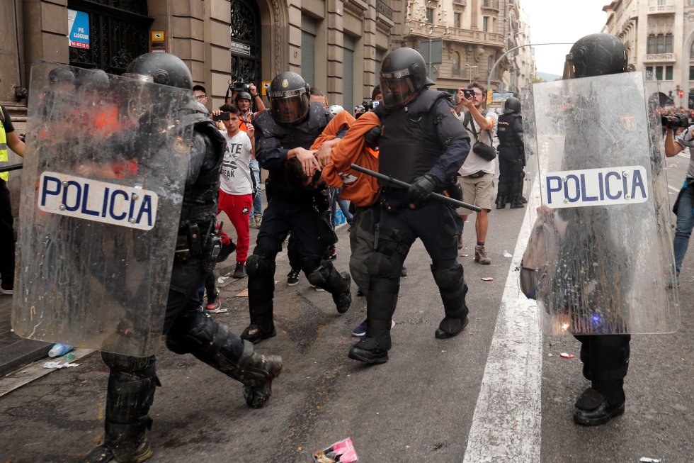 Agentes de policía trasladan a uno de los detenidos este viernes en Barcelona.