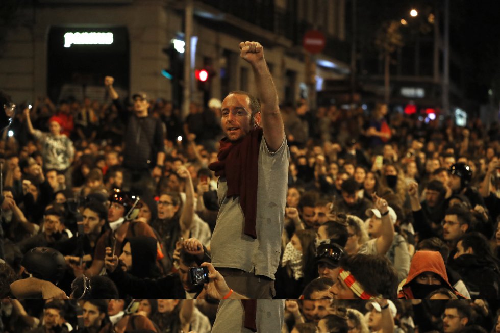 Un grupo de manifestantes llevan a cabo una sentada frente al cordón policial en la Plaza Urquinaona.