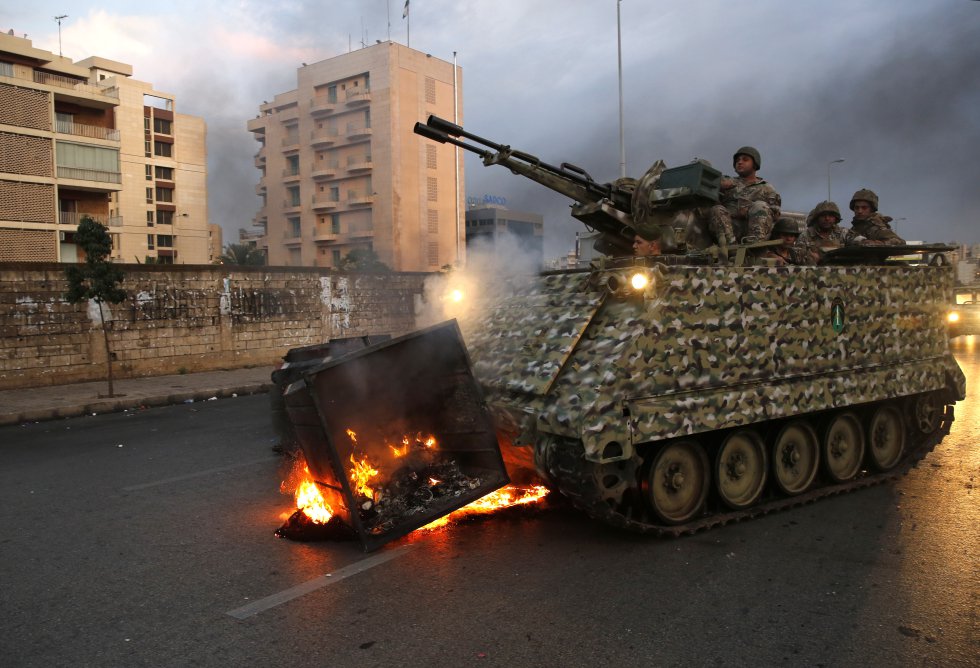 Un tanque del ejército retira un contenedor de basura incendiado por manifestantes en Beirut, Líbano.