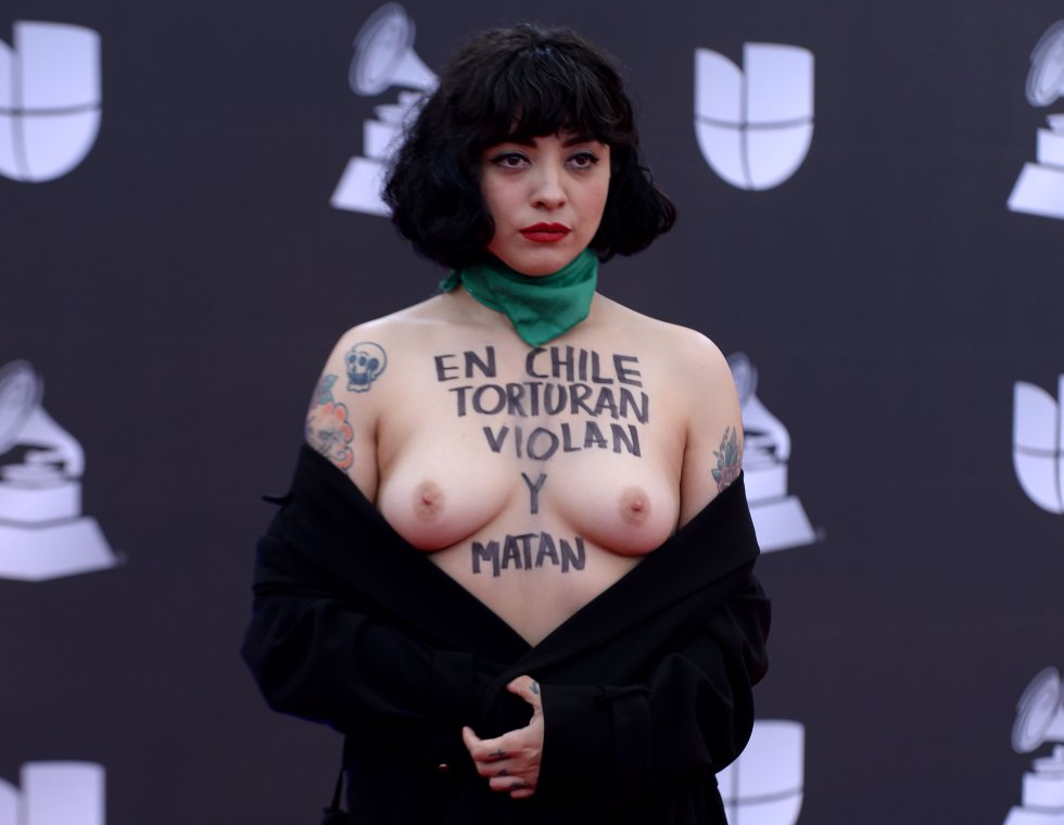 La cantante chilena Mon Laferte, expone su pecho en donde está escrito: "En Chile torturan, violan y matan", a su llegada a la 20a Entrega Anual del Latin Grammy en Las Vegas, el 14 de noviembre.rn