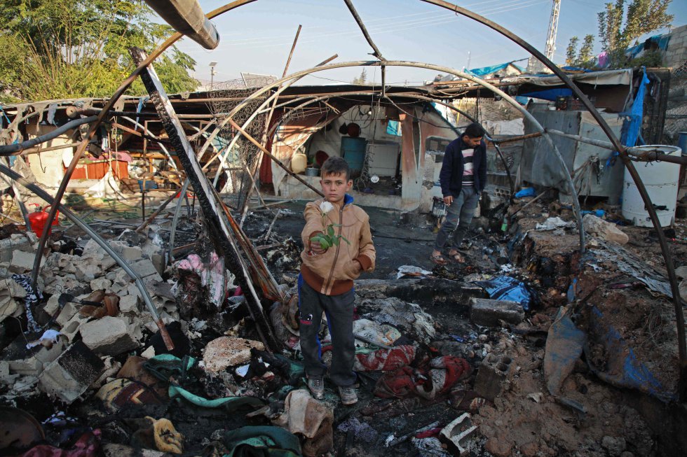 Un niño sostiene una rosa dentro de una carpa carbonizada tras el bombardeo del régimen sirio a un campamento improvisado en la aldea de Qah (Siria), el 21 de noviembre.