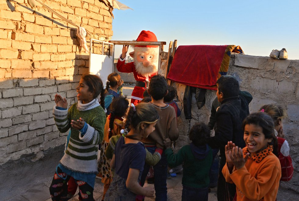 Un grupo de niños celebran la visita de un hombre vestido como Santa Claus en un barrio de la ciudad de Nayaf (Irak).