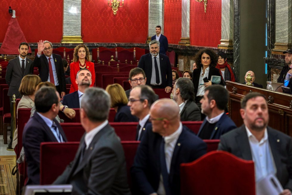 El presidente de la Generalitat, Quim Torra (al fondo, segundo por la izquierda), saluda a los doce líderes independentistas acusados por el proceso soberanista catalán que derivó en la celebración del 1-O y la declaración unilateral de independencia de Cataluña, en el banquillo del Tribunal Supremo, al inicio del juicio del 'procés', el 21 de febrero.