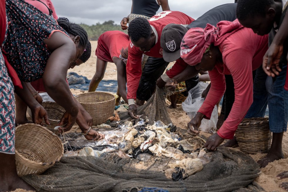 Varios pescadores retiran plásticos de las redes en la playa de Lomé, en Togo. El crecimiento de la población en la capital, consecuencia del éxodo rural, junto a los malos hábitos de los ciudadanos, provoca que la presencia de plásticos en la costa del área metropolitana esté creciendo drásticamente en los últimos años. Según el Foro Económico Mundial, el peso de residuos plásticos en mares y océanos superará al peso de todos los peces del planeta en 2050.