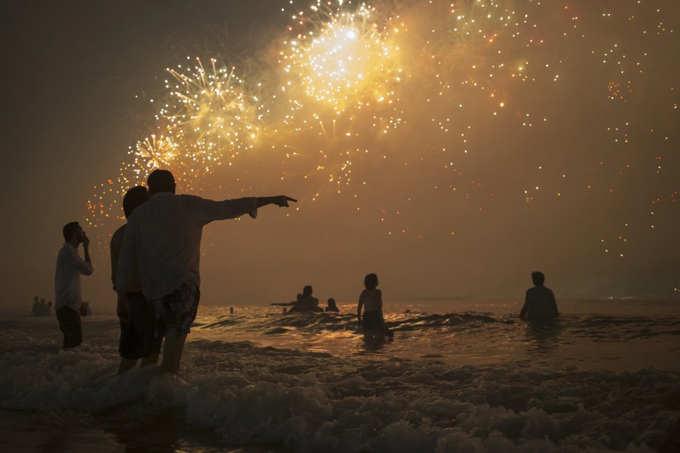 Una pareja admira los fuegos artificiales desde la playa de Copacabana, en Brasil.