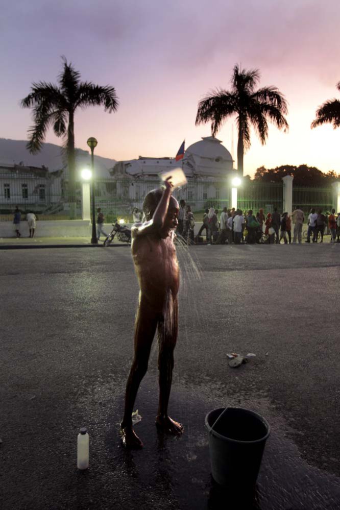 Uma das crianças refugiadas no campo instalado em frente ao palácio presidencial tenta se limpar na rua.