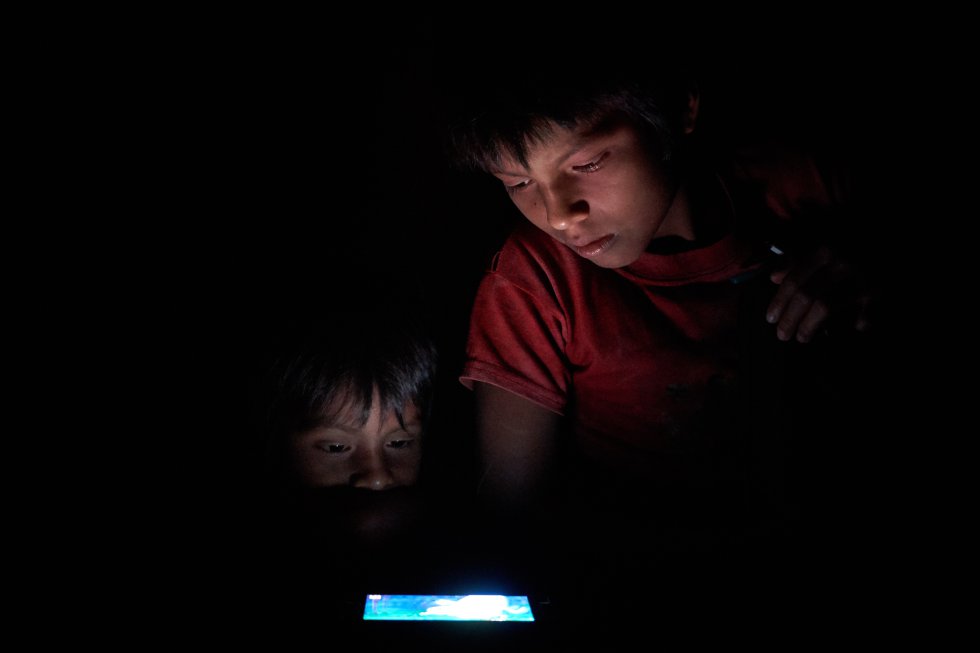 Dos hermanos miran dibujos animados en YouTube, antes de que se apague el Internet satelital en la comunidad de Sharamentsa.